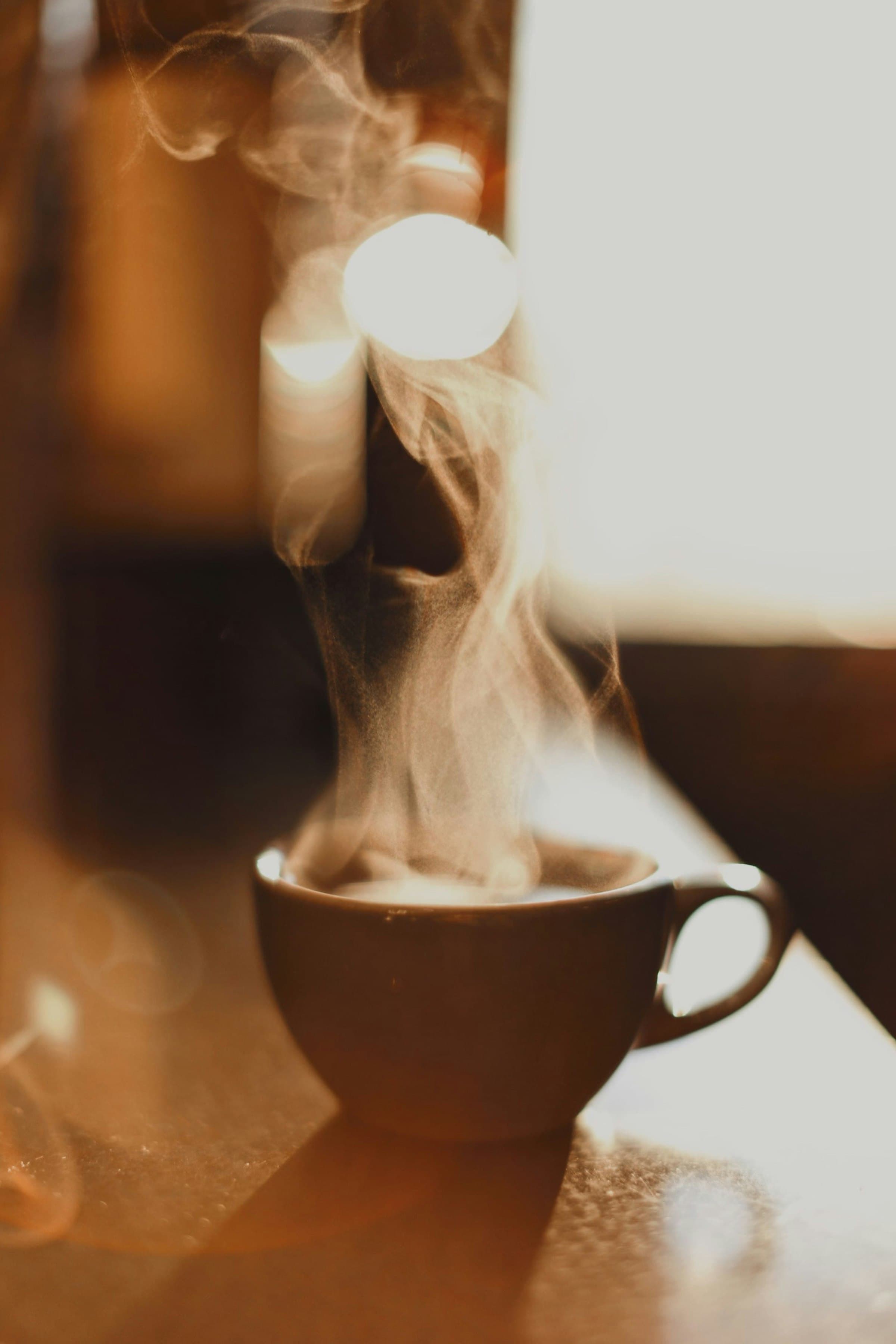 A steaming cappuccino backlit by golden morning window light